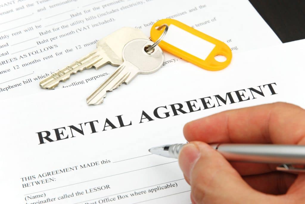 rental agreement form with signing hand and pen and keys