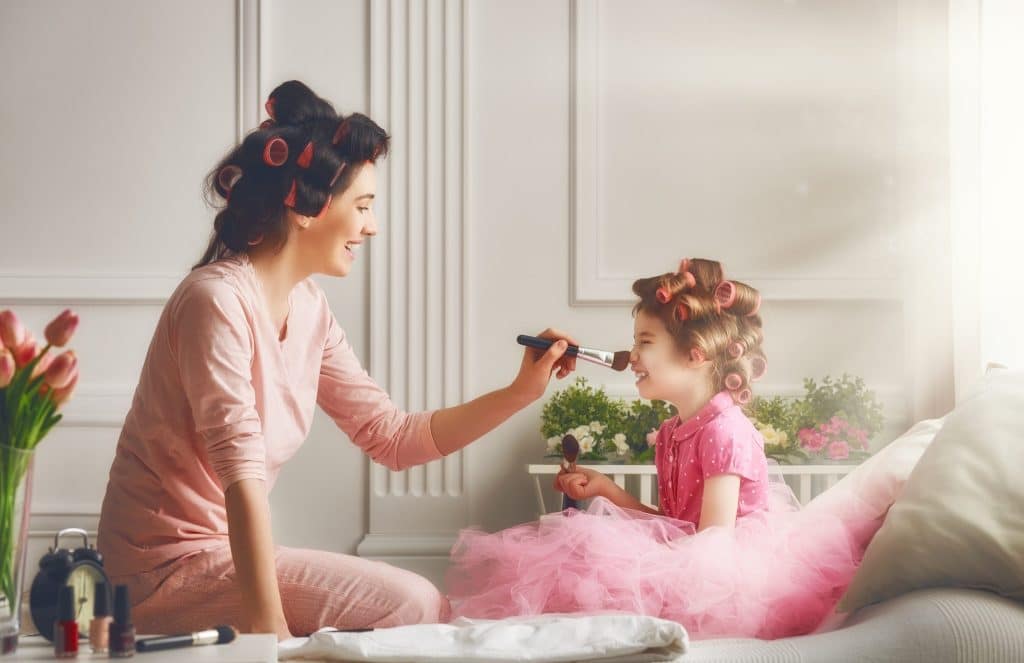 mom playing dress up with daughter inside their home