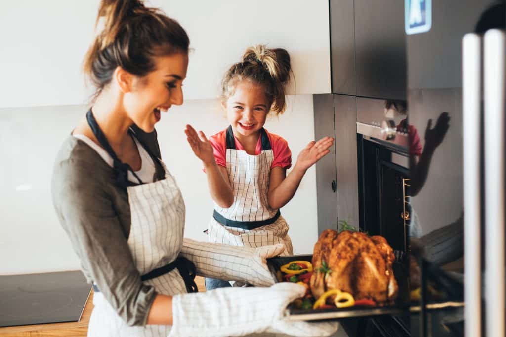 mom and daughter cooking thanksgiving dinner in kitchen