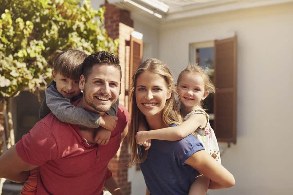 family shot with son on dad's back and daughter on mom's back