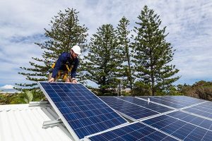 technician on roof installing a solar panel
