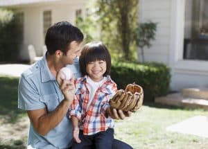 dad and son practicing baseball in front yard