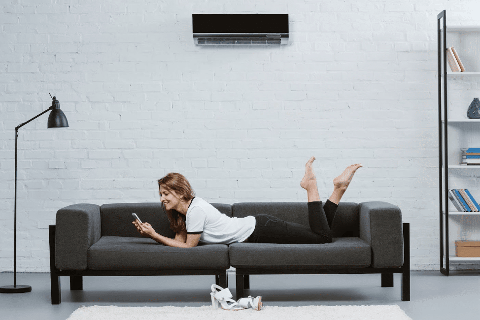 A female laying on the couch in her comfortable home with her AC system that removes humidity.